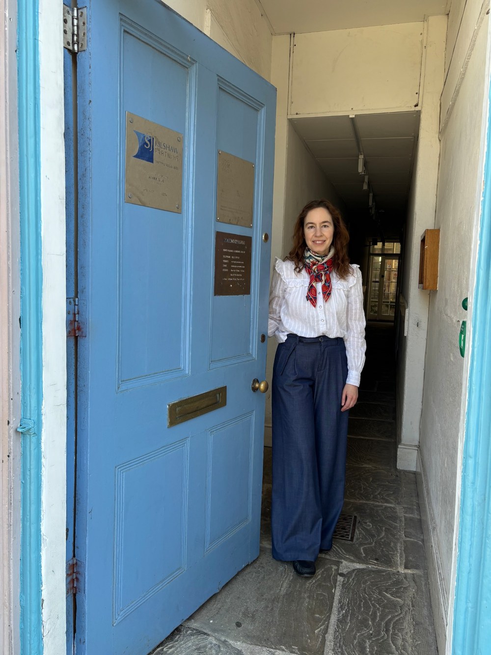 Dr Maria Valkovskaya standing in the blue doorway at the entrance to the practice.