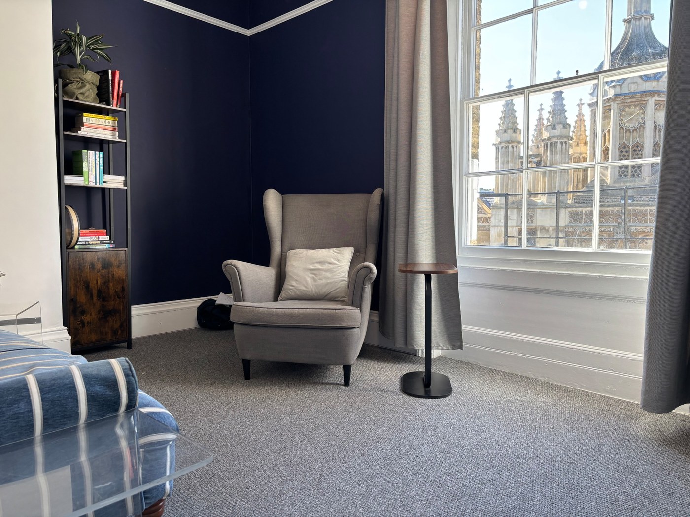 A calm therapy room with a grey armchair by the window in central Cambridge.